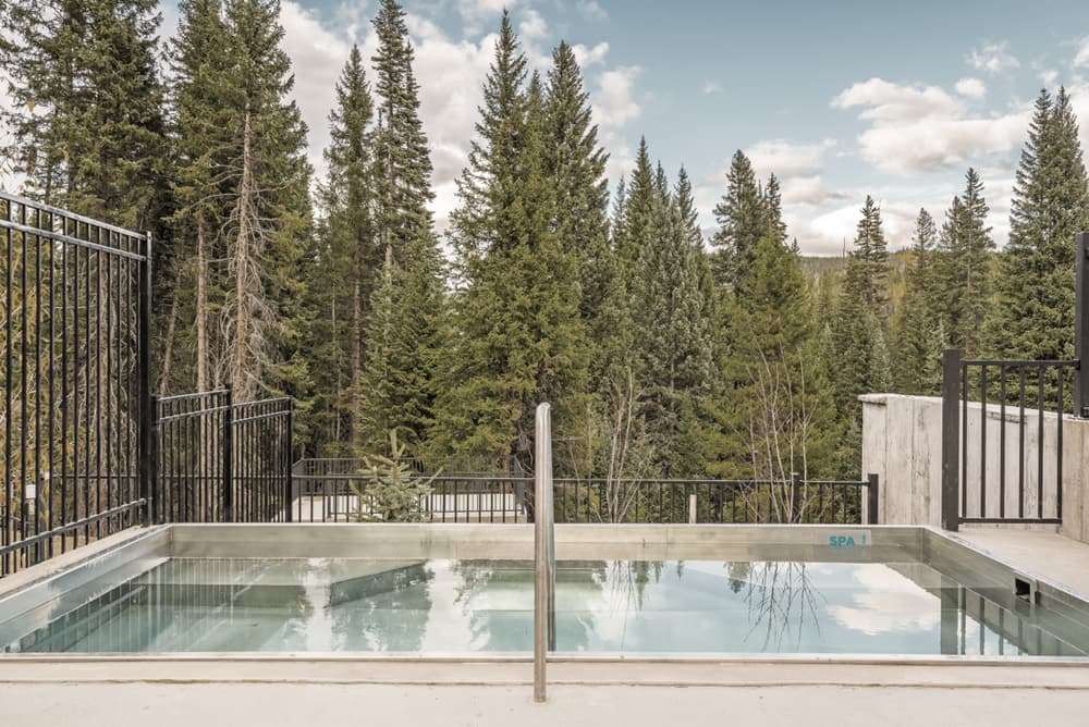 The club's outdoor pool and hot tub on a clear day, surrounded by pines